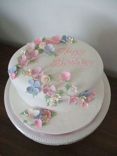 a birthday cake decorated with flowers and the words happy birthday on it's side