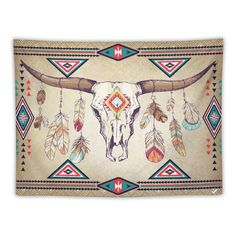 a bull skull with feathers on it's head is hanging from a wall tapestry