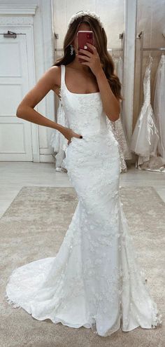 a woman taking a selfie while wearing a wedding dress in front of a mirror