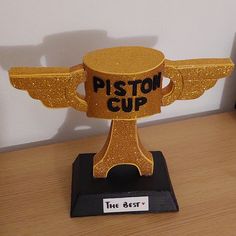 a plastic cup with wings on it sitting on top of a wooden table next to a wall