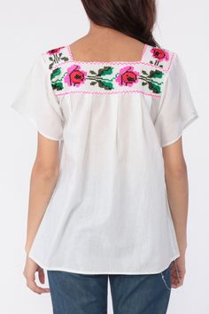 "Vintage Mexican blouse with floral embroidery on white cotton. Tunic cut. Every garment we sell is authentic vintage and one-of-a-kind! You will receive the exact item photographed. Condition: Very good vintage. Has a couple faint spots that should come out with cleaning. Best fits women's: Extra small Material: Feels like Cotton MEASUREMENTS Taken from seam to seam while the garment is lying flat. Double the armpit, waist, and hips For reference, model is 5'9\" and measures 33-25-36. Length fr White Bohemian Peasant Top With Chikankari Embroidery, White Peasant Top For Festival, White Folk Peasant Top For Festival, Beach White Cotton Peasant Top, Cotton Folk Peasant Top For Beach, White Cotton Peasant Top For Beach, Folk Style Cotton Peasant Top For Beach, Cotton Peasant Blouse With Embroidered Neckline, Folk Style Peasant Top With Floral Embroidery For Beach