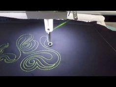 the machine is cutting fabric with green stitchs on it's sides and an intricate design