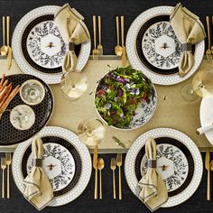 an overhead view of a table set with plates and silverware, napkins and gold - plated utensils