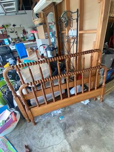 a wooden bed frame sitting inside of a room next to a door and shelves filled with clutter