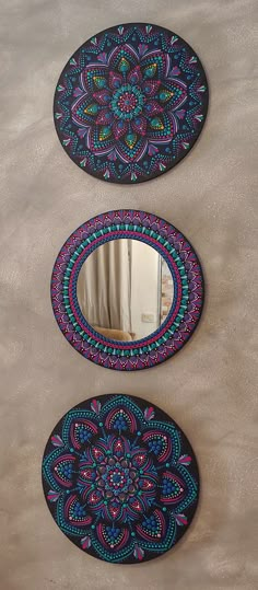 three circular mirrors with designs on them are hanging on the wall next to each other