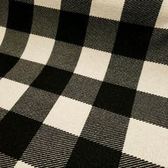 a black and white checkered blanket is laying on the floor with it's diagonal pattern