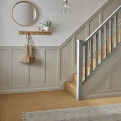 a hallway with beige carpeting and white painted walls, along with a wooden bannister on the wall