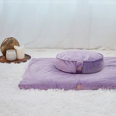 a purple pillow sitting on top of a white fluffy rug next to a candle holder