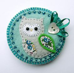 an owl ornament is hanging on a white surface with blue and green accents