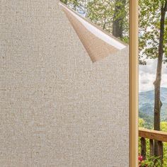 an open window with a view of trees and mountains in the back ground, looking out onto a wooded area