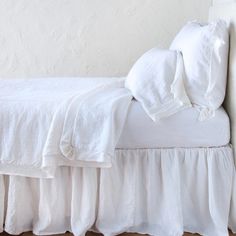 a bed with white linens and ruffled bedspread on top of it