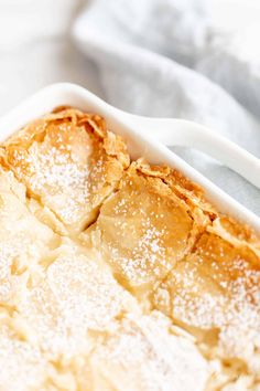 a white dish filled with food covered in powdered sugar on top of a table