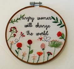 a cross - stitch hoop hanging on a wall with the words,'angry women will change the world '