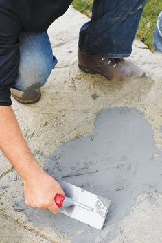 a man is painting concrete with a red paintbrush and some other people are looking on