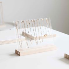 several necklaces are on display in a clear acrylic holder with wooden base