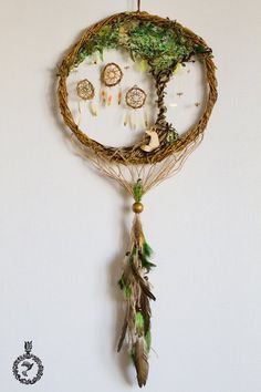 a dream catcher hanging on the wall with feathers and leaves attached to it's sides