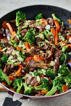 beef and broccoli stir fry in a wok with tongs on the side