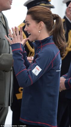 a woman in uniform is clapping while other people stand behind her and talk to each other