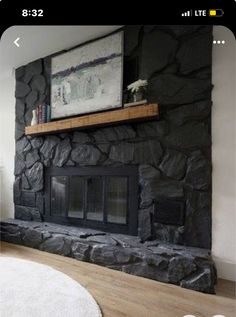 a living room with a large stone fireplace and white rugs on the hardwood floor