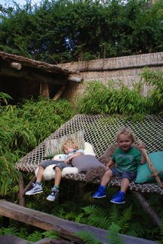 two children are sitting in a hammock outside