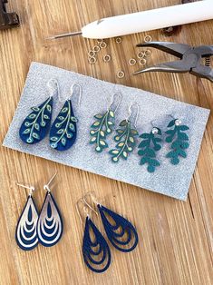 several pairs of earrings sitting on top of a wooden table