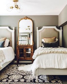 a bedroom with two beds and a mirror on the wall next to eachother