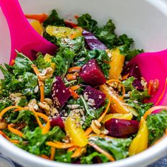 a white bowl filled with salad and pink spoons