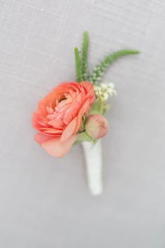 an orange flower on a white vase with green leaves and flowers in it's center