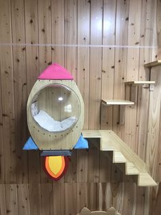 a child's play area with wooden walls and shelves, including a toy rocket ship