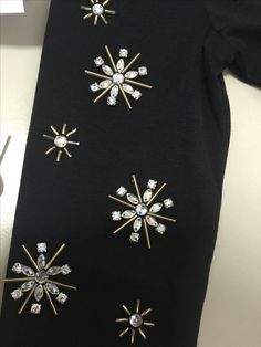 a black tie with four different types of brooches on it, all in gold and white