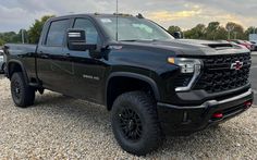 a black truck is parked in the gravel