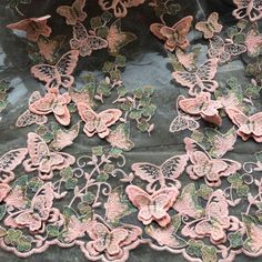 some pink and green butterflies on a black cloth with white stitching in the middle