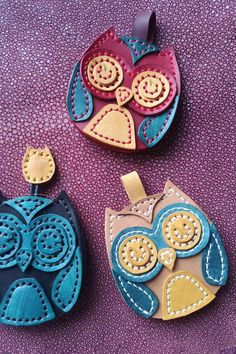 three handmade owl ornaments sitting on top of a purple surface