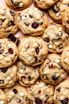 cookies with white chocolate chips and cranberries are arranged on a pink surface, top view