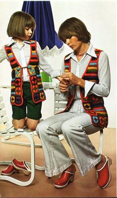 two children sitting on a white chair wearing colorful vests