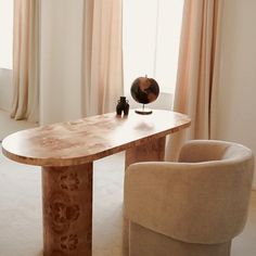 a wooden table sitting next to two chairs in front of a window with drapes