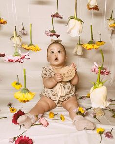 a baby is sitting in front of flowers