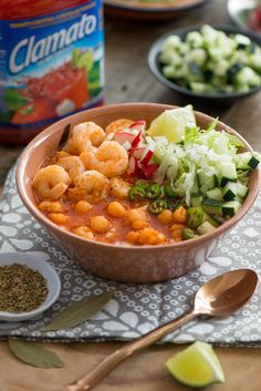 a bowl filled with shrimp and vegetables next to a can of clamata soup