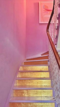 the stairs are painted pink and have wooden handrails that lead up to the second floor