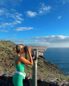 a woman is looking at the ocean with binoculars