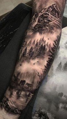 a man's arm with trees and mountains on it