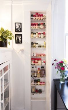 the pantry door is open to reveal what's in the room, and there are flowers on the table next to it