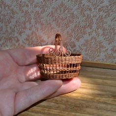 a hand holding a miniature wicker basket