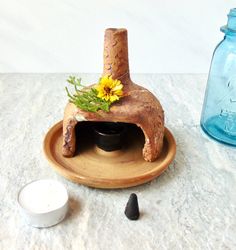 a clay oven with flowers in it sitting on a plate next to some salt and pepper shakers