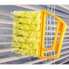 a yellow dust mop hanging on the side of a window sill next to blinds