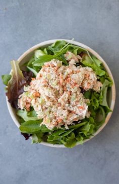 a salad in a bowl with lettuce and carrots on top, ready to be eaten