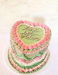 a heart shaped cake with pink, green and white frosting that says i love you