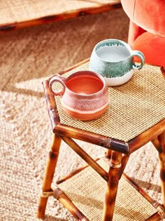 a small table with a cup and saucer on top of it next to a red chair