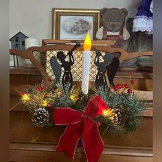 a lit candle sitting on top of a wooden table in front of a christmas wreath