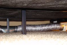 a close up of a metal pipe under a bed frame on the carpeted floor